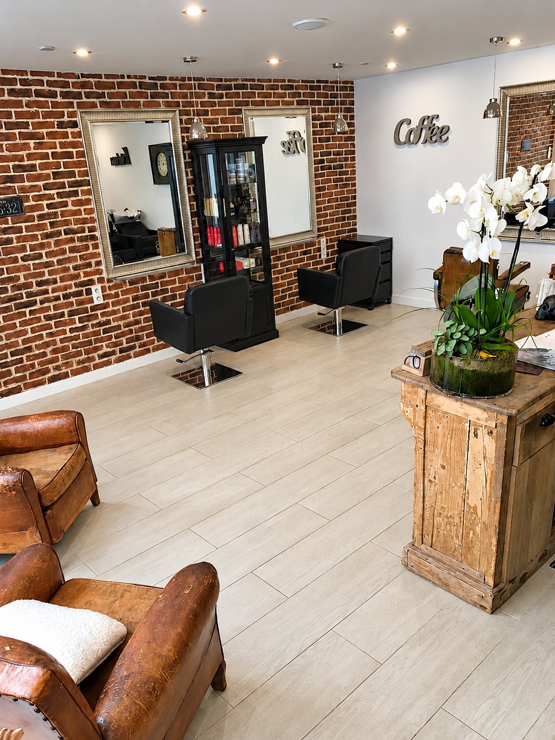 Salon vu depuis les fauteuils en cuir : orchidée blanche sur un meuble en bois et mur de briques.